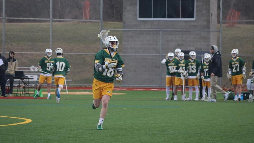 Mark Frascello runs up the field with his team's sideline looking on behind him. 