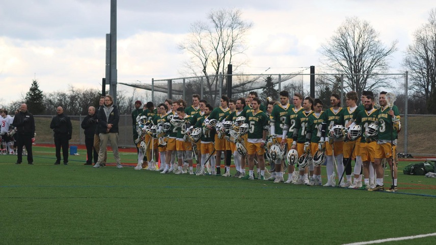 The SUNY Delhi men's lacrosse team stands on the sideline during the national anthem.