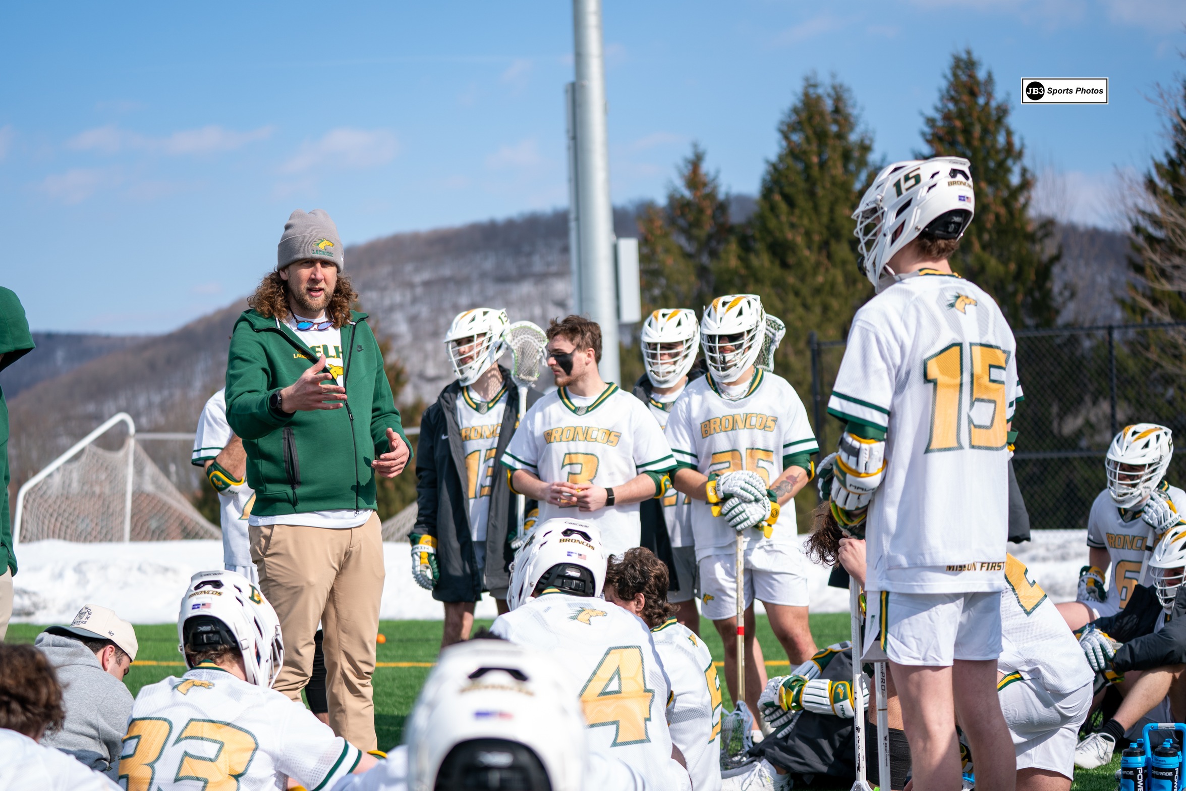 Coach Miller addresses the team, who is huddled around, following their home-opening win against Marywood.