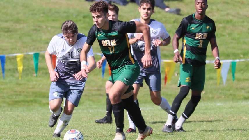 Carlos Del Monte taking the ball up the field with several opponents behind him.